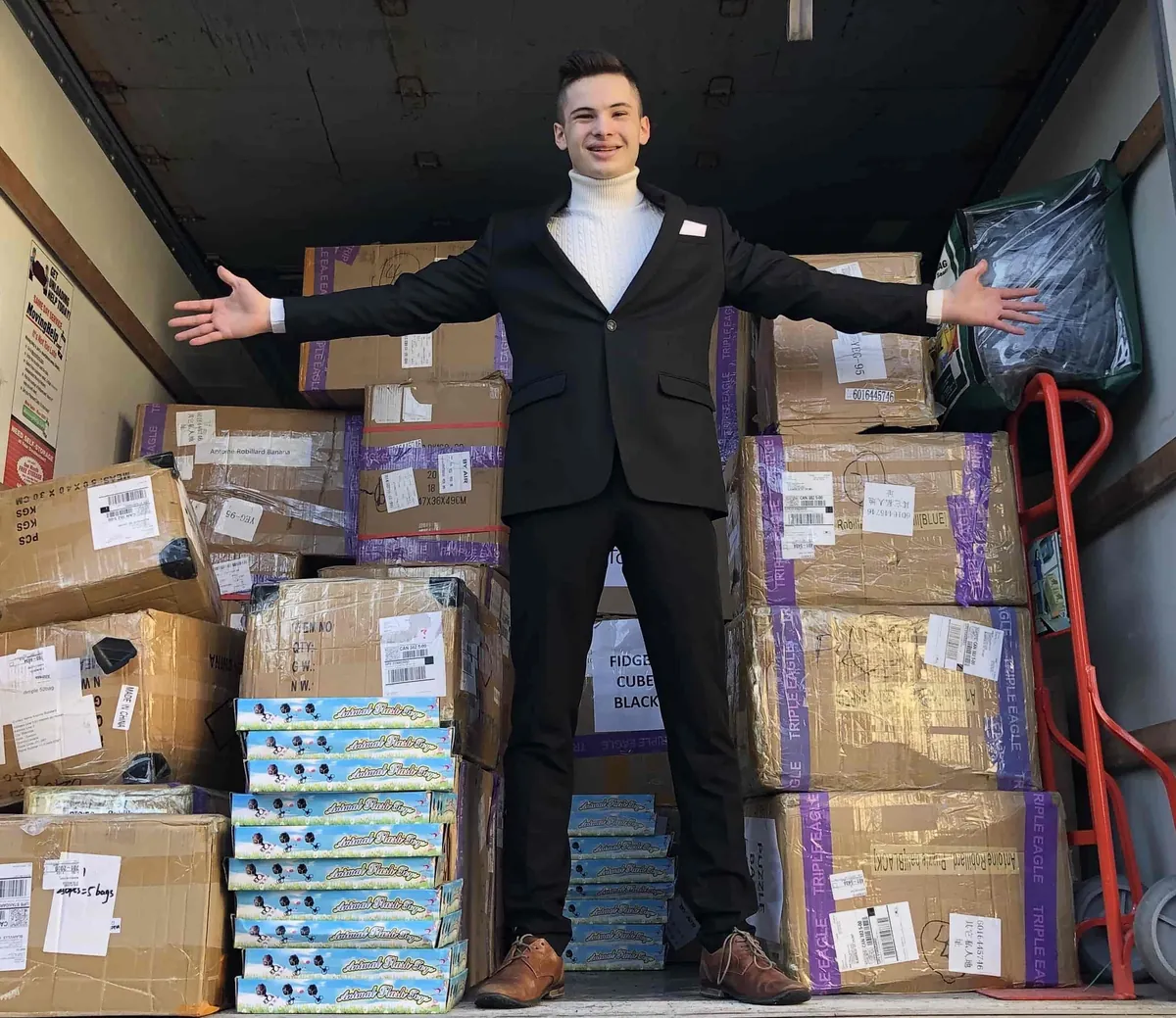 Antoine Robillard, fondateur de Robiii, debout dans un camion de livraison rempli de boîtes de produits Robiii