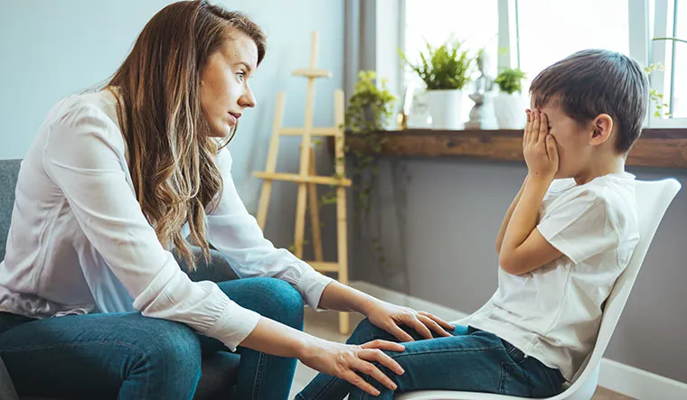 Mère qui réconforte doucement un jeune garçon qui se cache le visage dans les mains