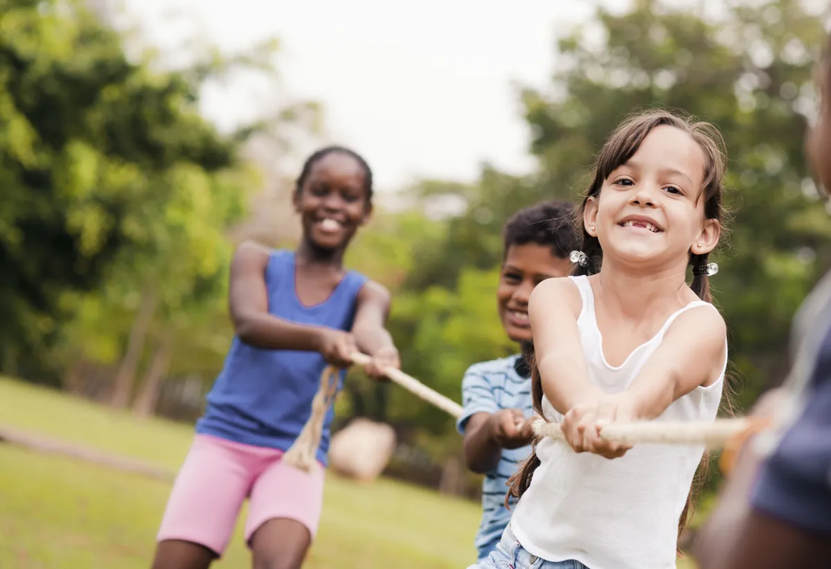 Enfants qui jouent au tir à la corde dehors, développant force et esprit d'équipe