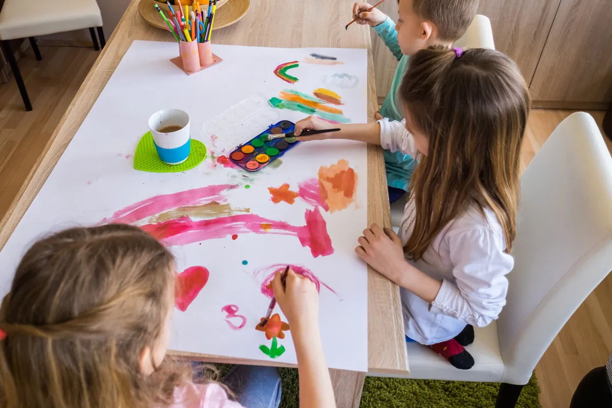 Enfants qui peignent ensemble sur une grande feuille de papier à table