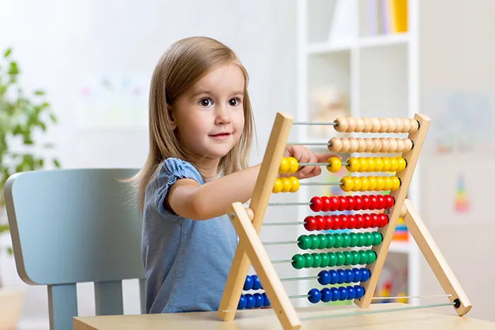 Fillette concentrée qui fait glisser les billes d'un boulier coloré
