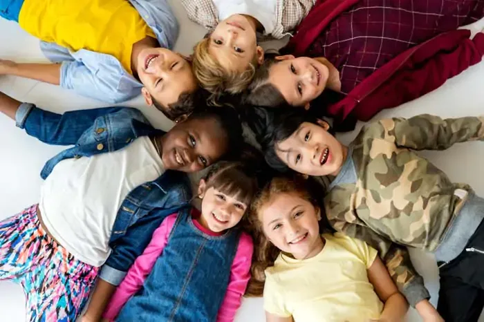 Cercle d'enfants souriants couchés tête contre tête sur le plancher