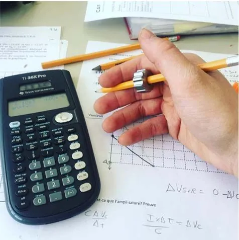 Fidget Rolliii qui tourne sur un crayon pendant qu'un élève fait ses devoirs de maths avec une calculatrice