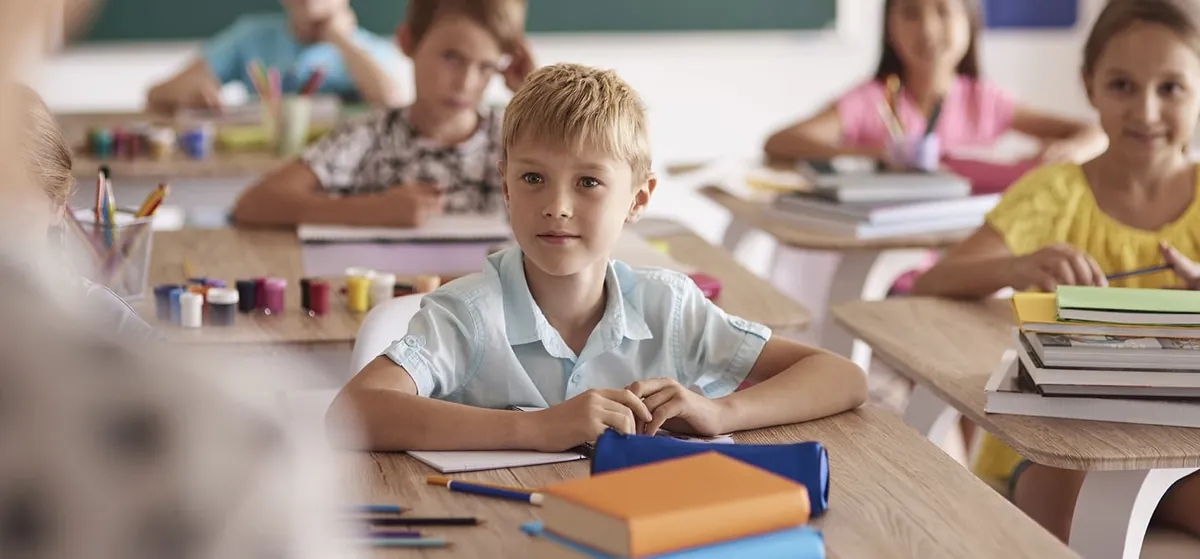 Jeunes élèves assis à leur pupitre dans une classe lumineuse