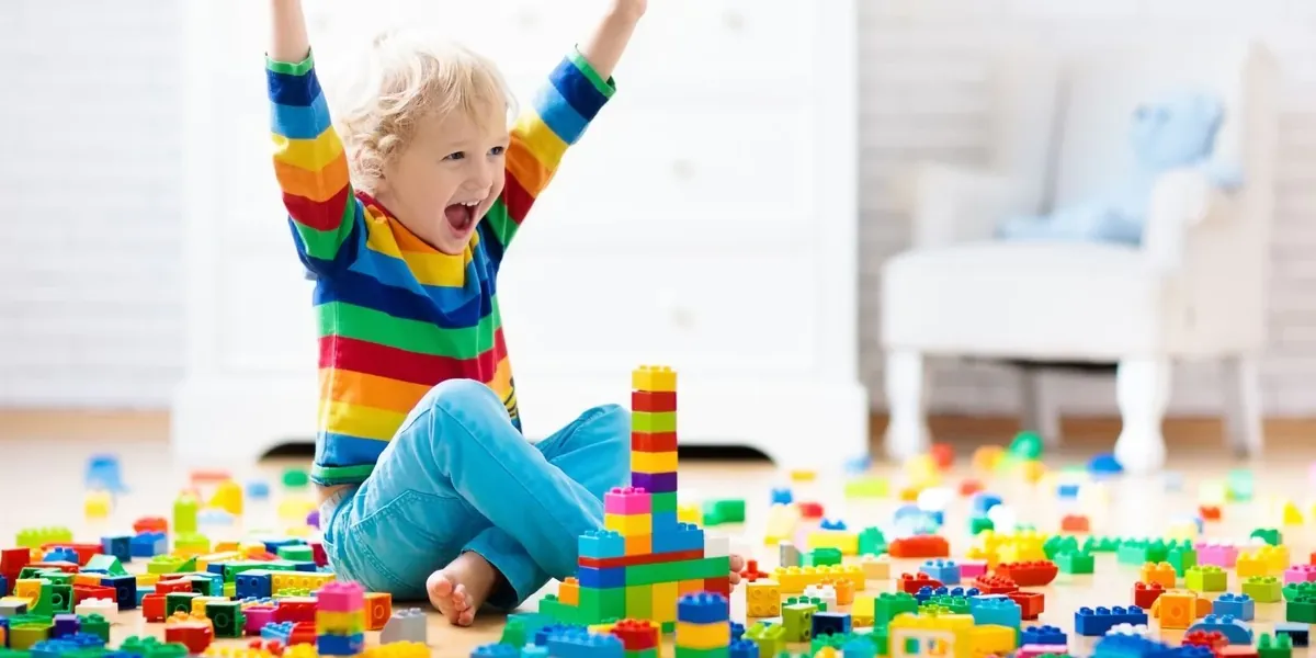 Jeune enfant heureux entouré de briques de construction colorées au sol