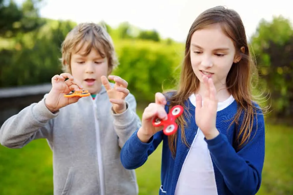 Deux enfants qui jouent avec des fidget spinners dehors