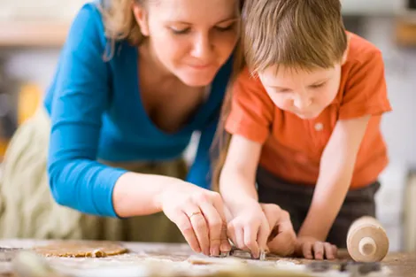 Une adulte guide doucement les mains d'un enfant pendant une activité concrète