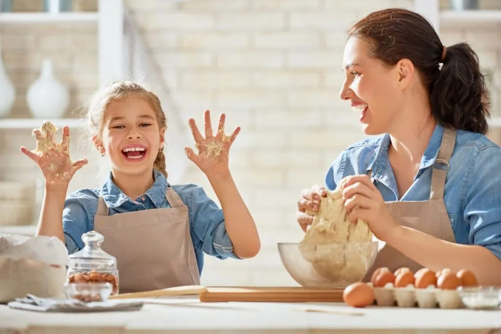 Une mère et sa fille qui pétrissent de la pâte ensemble dans la cuisine — une activité de vie pratique