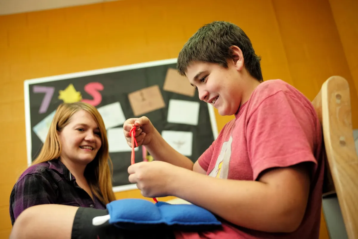 Adolescent autiste qui pratique une habileté concrète avec une technicienne en éducation spécialisée à l'école