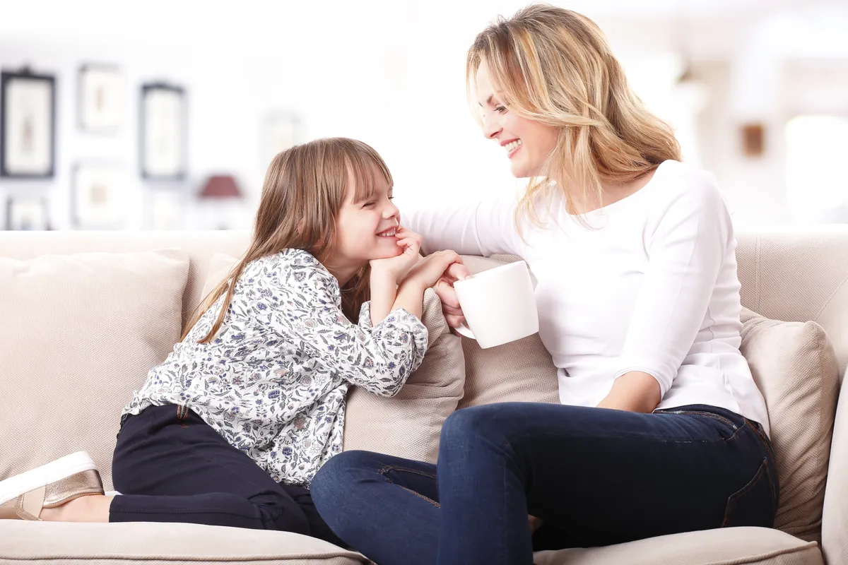 Mère qui se détend sur le divan avec sa fille, un moment de repos et de complicité