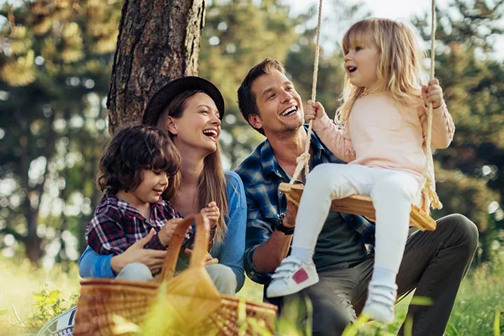 Famille qui pique-nique en plein air pendant qu'une fillette se balance sur une balançoire