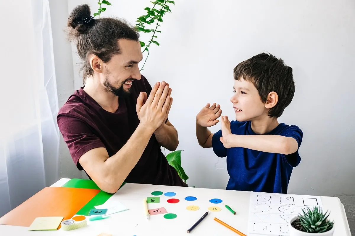 Père et fils qui se tapent dans la main pendant une activité d'apprentissage avec des cartes visuelles