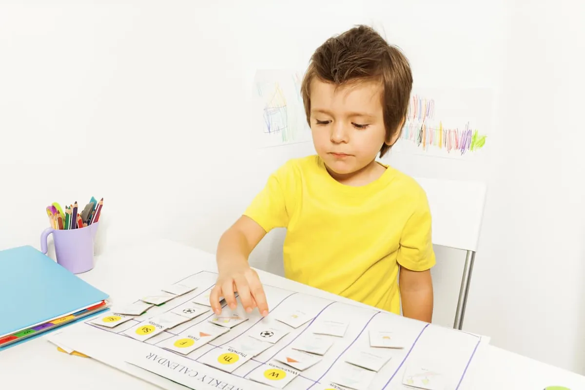 Jeune garçon qui place des pictogrammes sur un horaire visuel pour suivre sa routine quotidienne