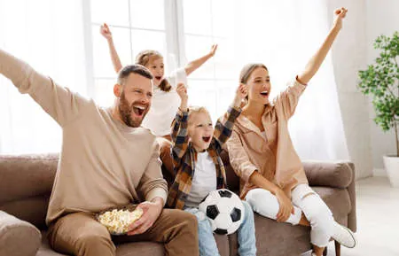 Famille qui applaudit ensemble sur le divan pour célébrer une petite victoire