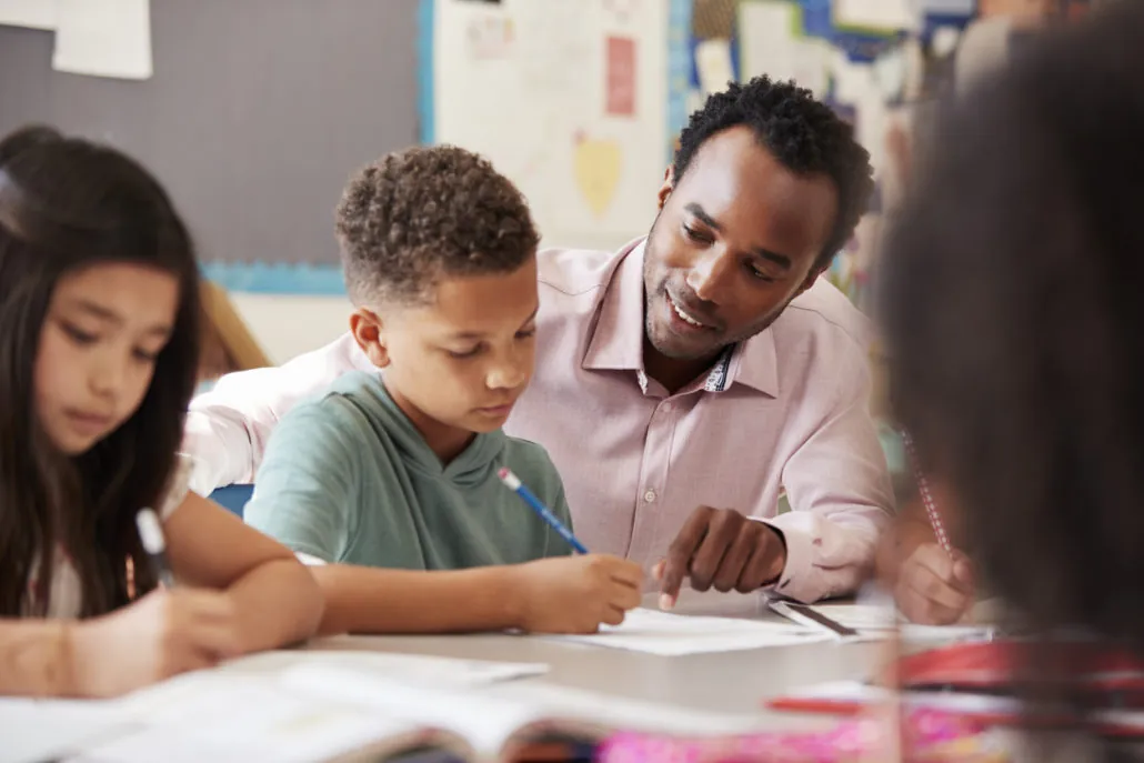 Enseignant qui aide des élèves dans leur travail en classe
