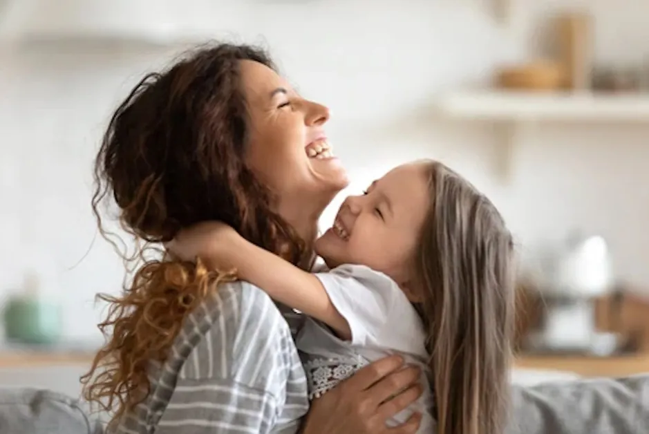 Mère et fille qui rient ensemble en se serrant dans leurs bras à la maison