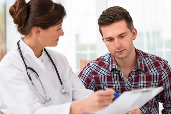 Médecin qui passe en revue une évaluation du TDAH avec un patient en consultation
