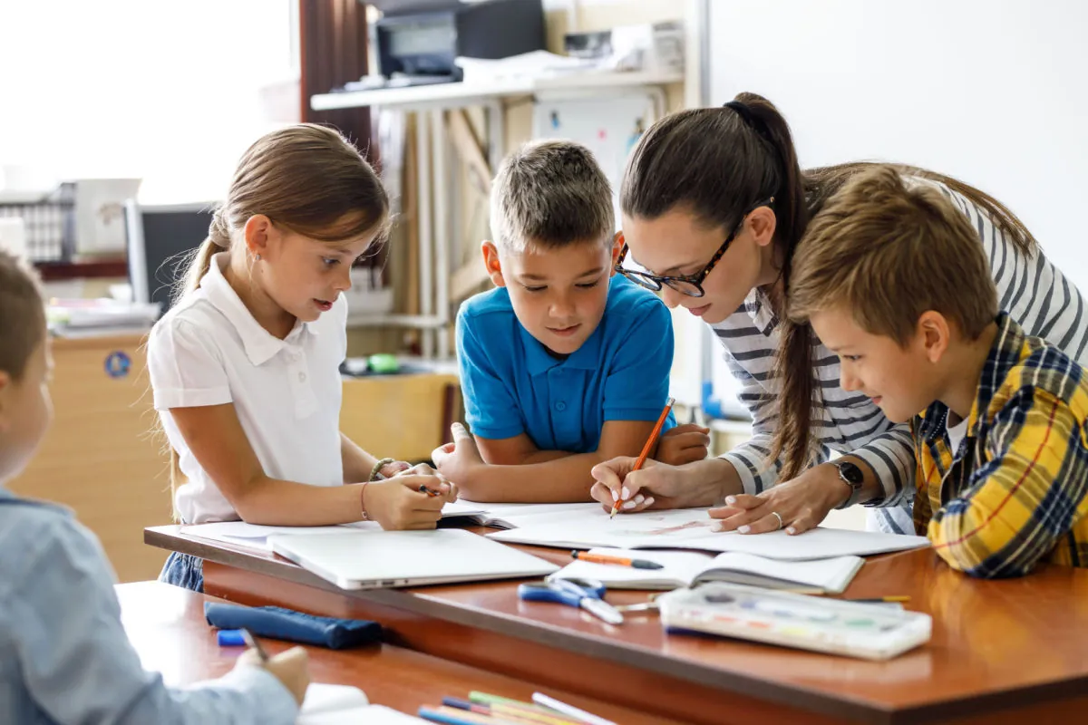 Enfants qui réalisent ensemble une activité d'apprentissage à une table, guidés par une adulte