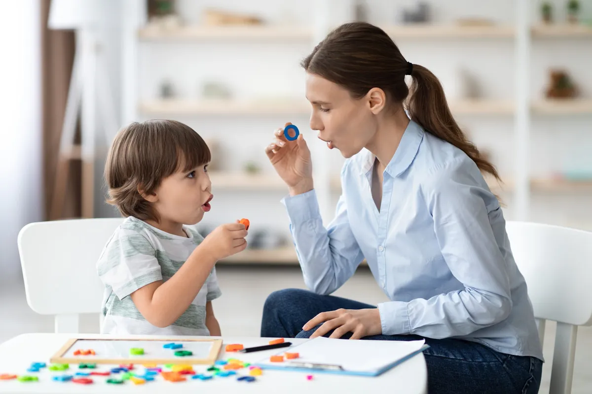 Adulte et jeune enfant qui discutent pendant une activité de jeu avec des pièces colorées, pour soutenir le développement du langage