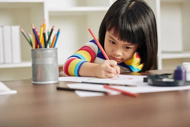 Fillette concentrée sur un dessin coloré à son bureau, un exemple de jeu libre créatif