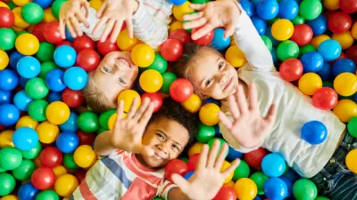 Enfants souriants couchés dans une piscine à balles colorées pendant un jeu sensoriel