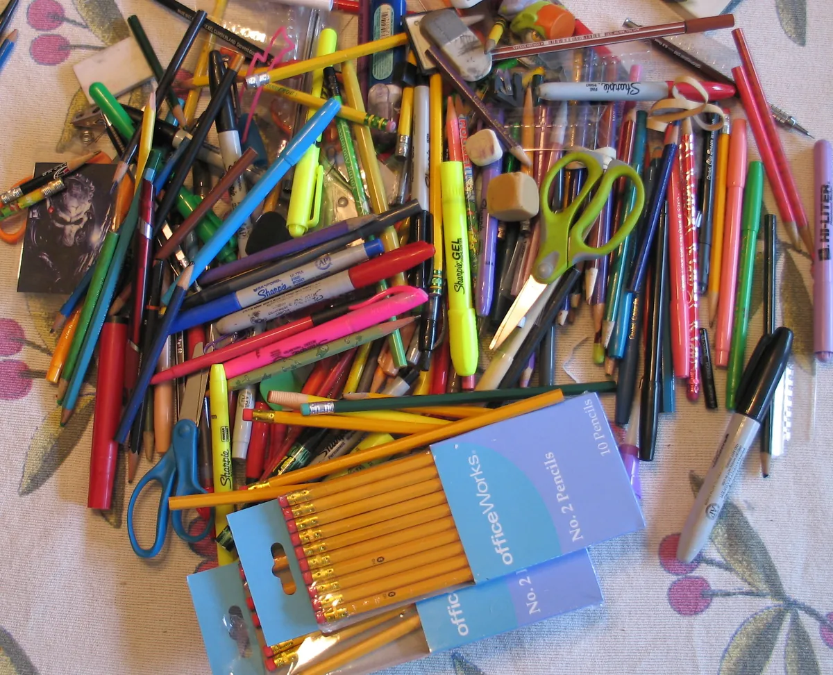Pile de crayons, de marqueurs, de ciseaux et de stylos récupérés pour être réutilisés avant d'acheter de nouvelles fournitures