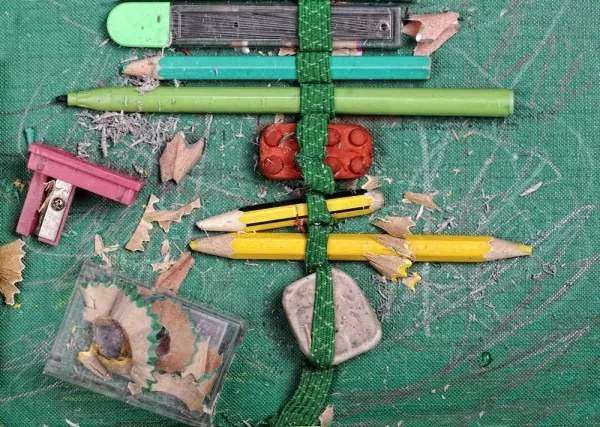 Fournitures scolaires économiques — crayons, taille-crayon, gomme à effacer et marqueur — sur un tapis de coupe vert