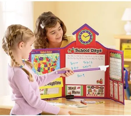 Deux fillettes qui jouent à l'école avec un décor de classe miniature et une baguette
