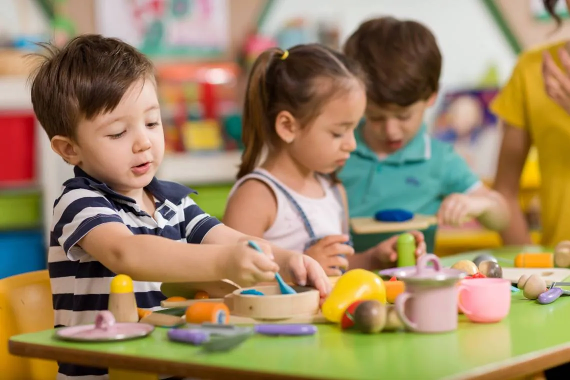 Enfants d'âge préscolaire qui jouent ensemble à la cuisine avec de la nourriture et de la vaisselle jouets