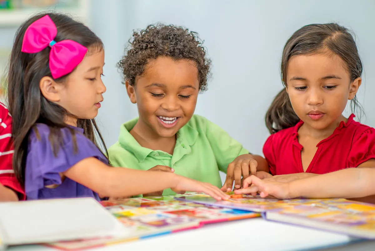 Trois enfants d'origines diverses qui font un casse-tête ensemble à une table