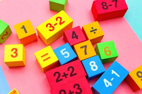 Cubes de bois colorés affichant des chiffres et des opérations simples comme 3 − 2 et 4 − 1