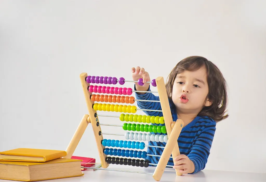 Jeune enfant qui compte les billes d'un boulier en bois coloré