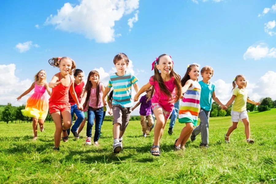Groupe d'enfants qui courent joyeusement dans un champ pendant le jeu libre