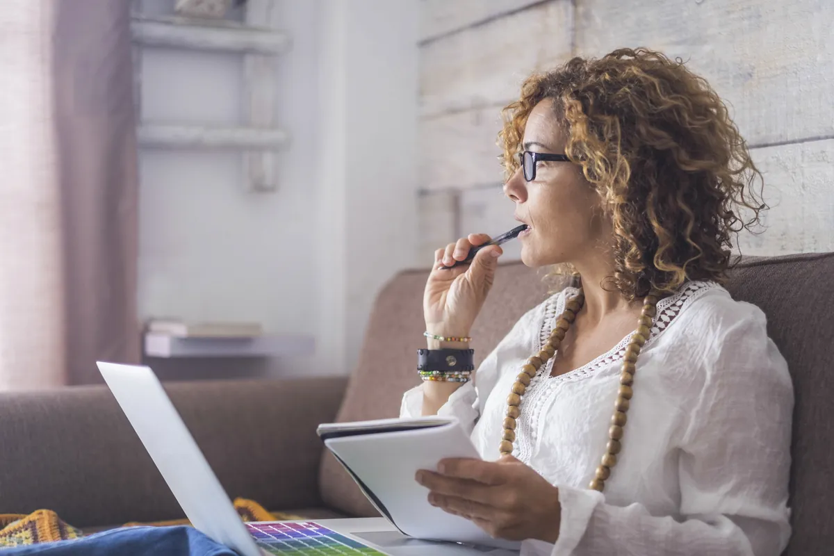 Femme perdue dans ses pensées, stylo et carnet en main — l'inattention passe souvent inaperçue, surtout chez les filles et les femmes