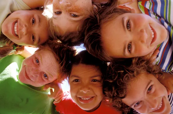 Cercle de visages d'enfants souriants penchés vers l'objectif