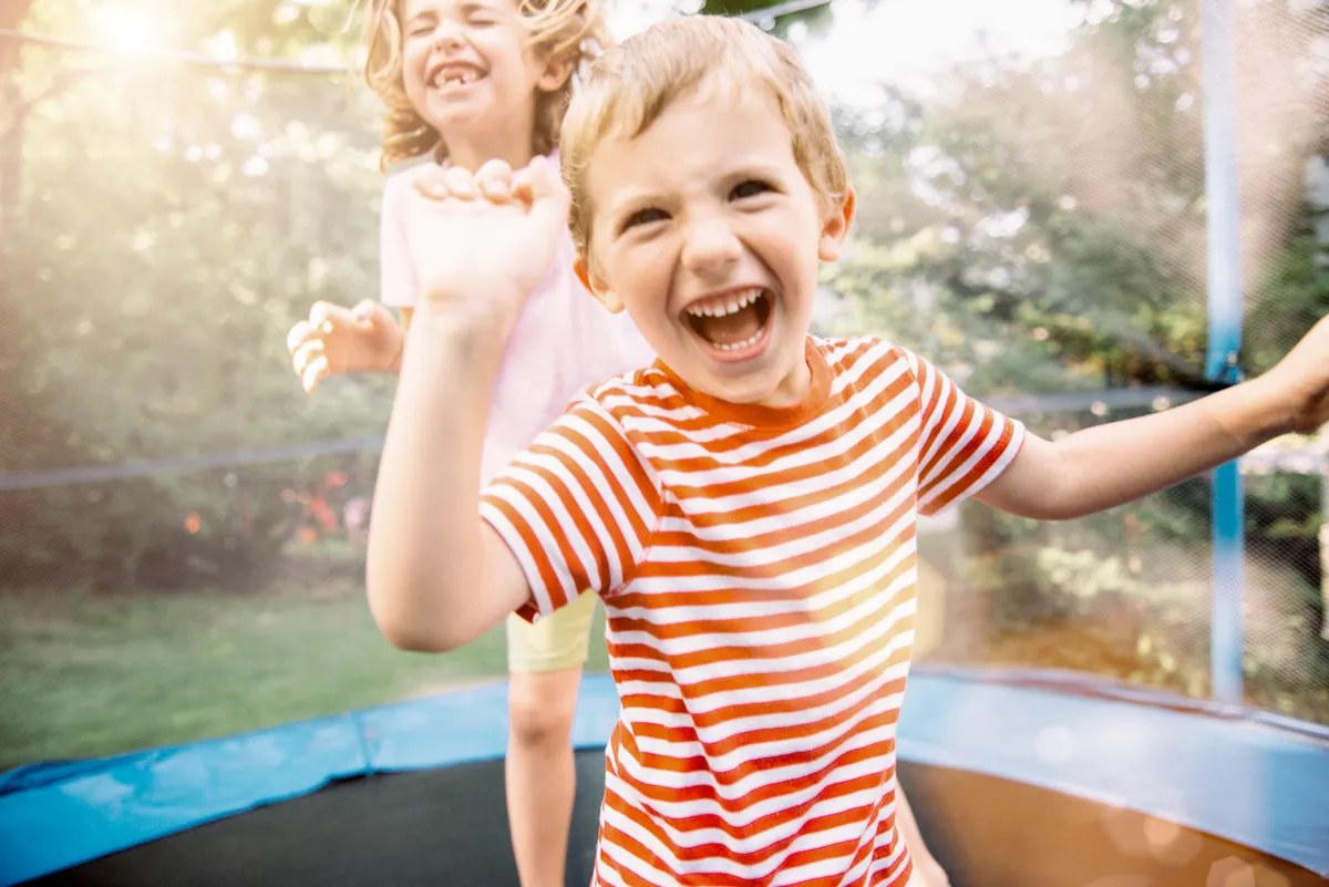 Garçon plein d'énergie qui saute et rit sur un trampoline dans la cour