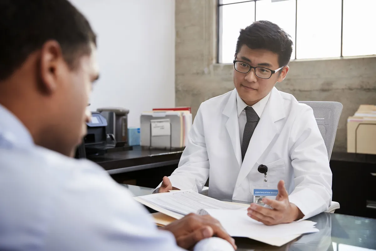 Spécialiste en sarrau qui discute des résultats d'une évaluation avec un patient à son bureau