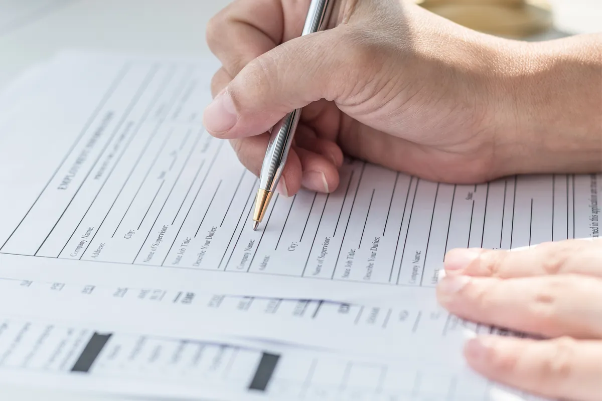 Main qui remplit un formulaire d'évaluation avec un stylo