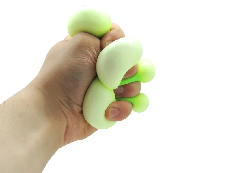 Main qui presse la balle Doh Squishy, la pâte déborde entre les doigts