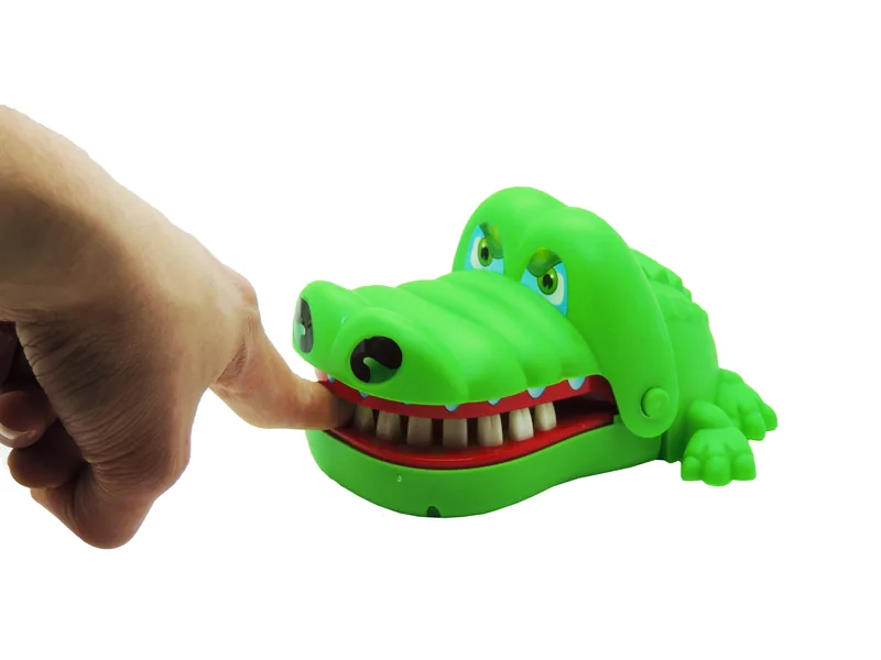 Un doigt appuie sur une dent du crocodile, gueule ouverte